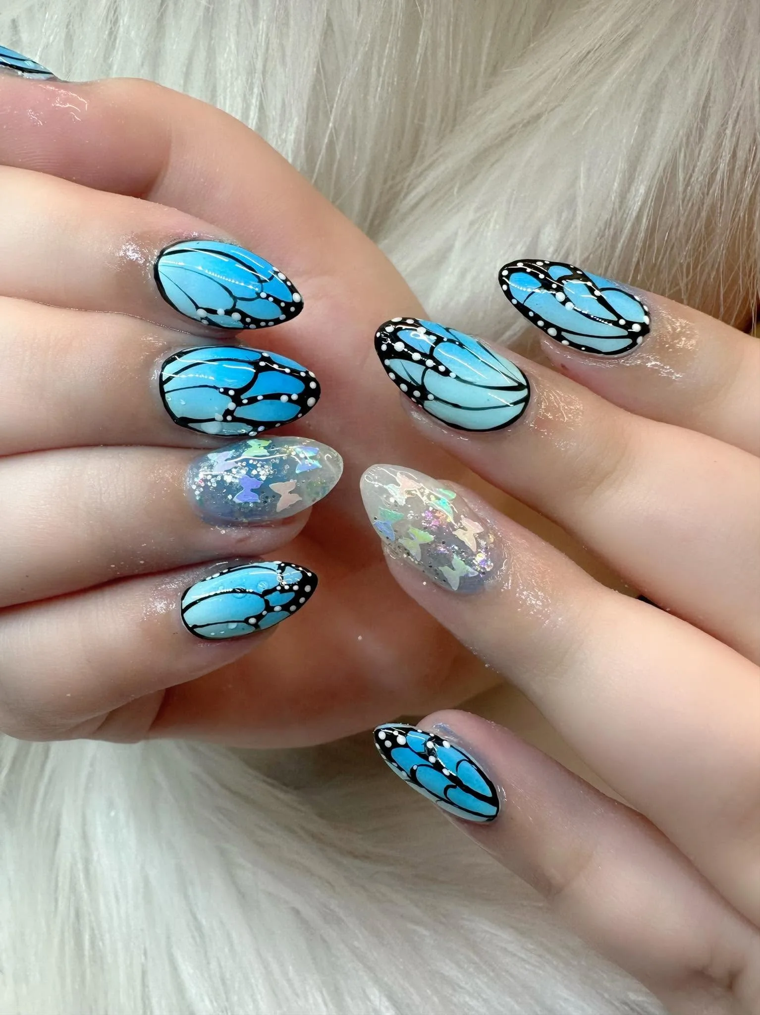 Blue butterfly-wing painted almond nails with glitter star accent nails