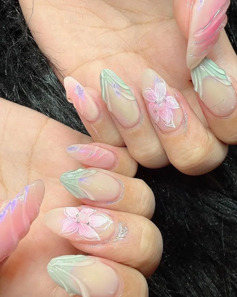 Sheer nude almond nails with 3D pink flowers, sage leaves and pearl accents